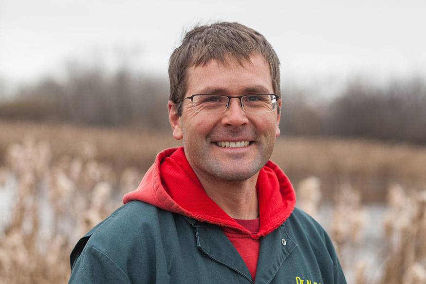 Headshot of Dr. Nathan Erickson standing outside in coveralls and a red hoodie